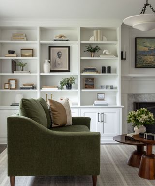 A living room with white built-in bookshelves and a dark green couch