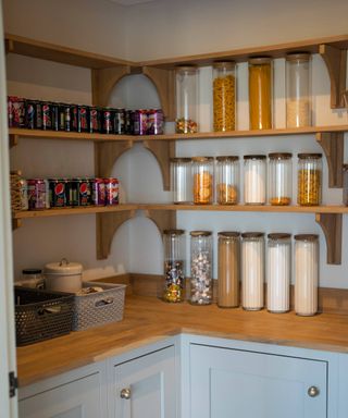 walk in pantry with grey shaker cabinets, wooden worktop and open shelving with glass storage jards and rows of cans