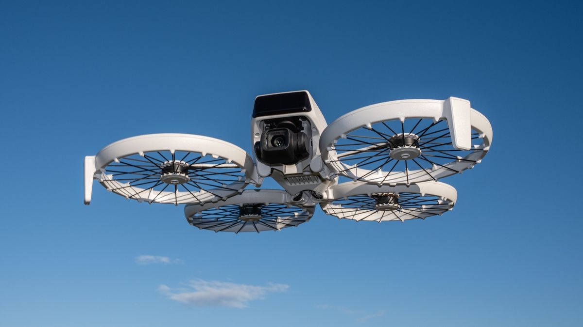 The DJI Flip drone, in white with four propellers is mid flight with clear blue skies behind it and one small gray cloud just below it.