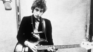 Bob Dylan posing for a photograph with a bass guitar