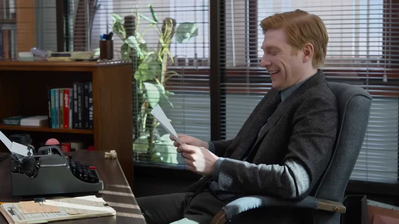 Domhnall Gleesonは微笑んで紙の中で論文を読んでいます。