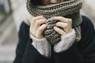 A close up of a woman holding a knitted scarf