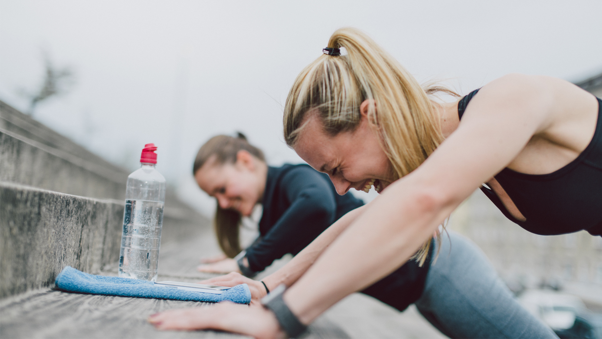 Two women wearing fitness trackers working out