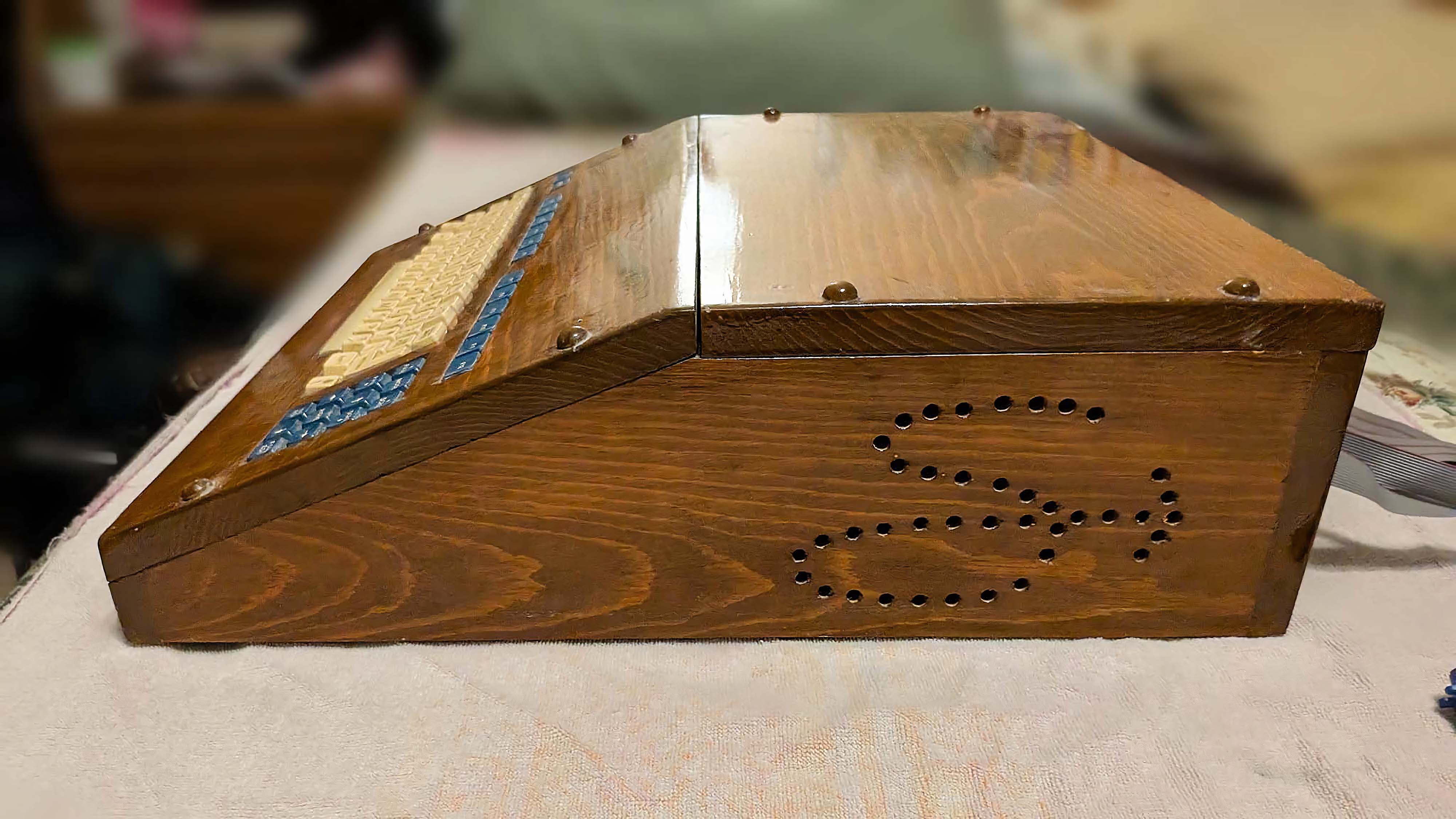A side view of a customized computer built in 1982 with a wooden case that has a cursive "S" drilled into the side for air vents.