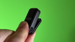 RØDE Wireless Micro microphone transmitter held in a hand in front of a green screen