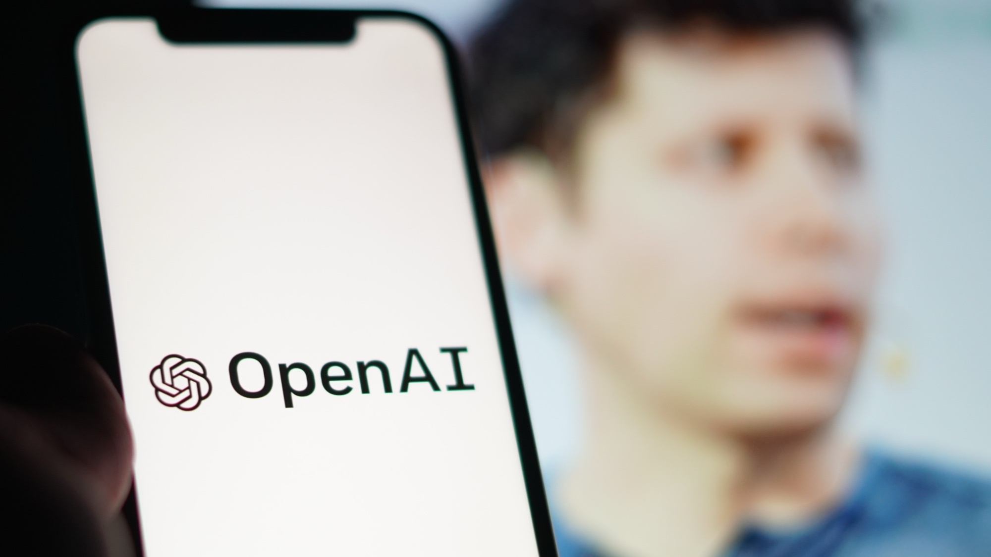 A phone saying OpenAI with Sam Altman behind it