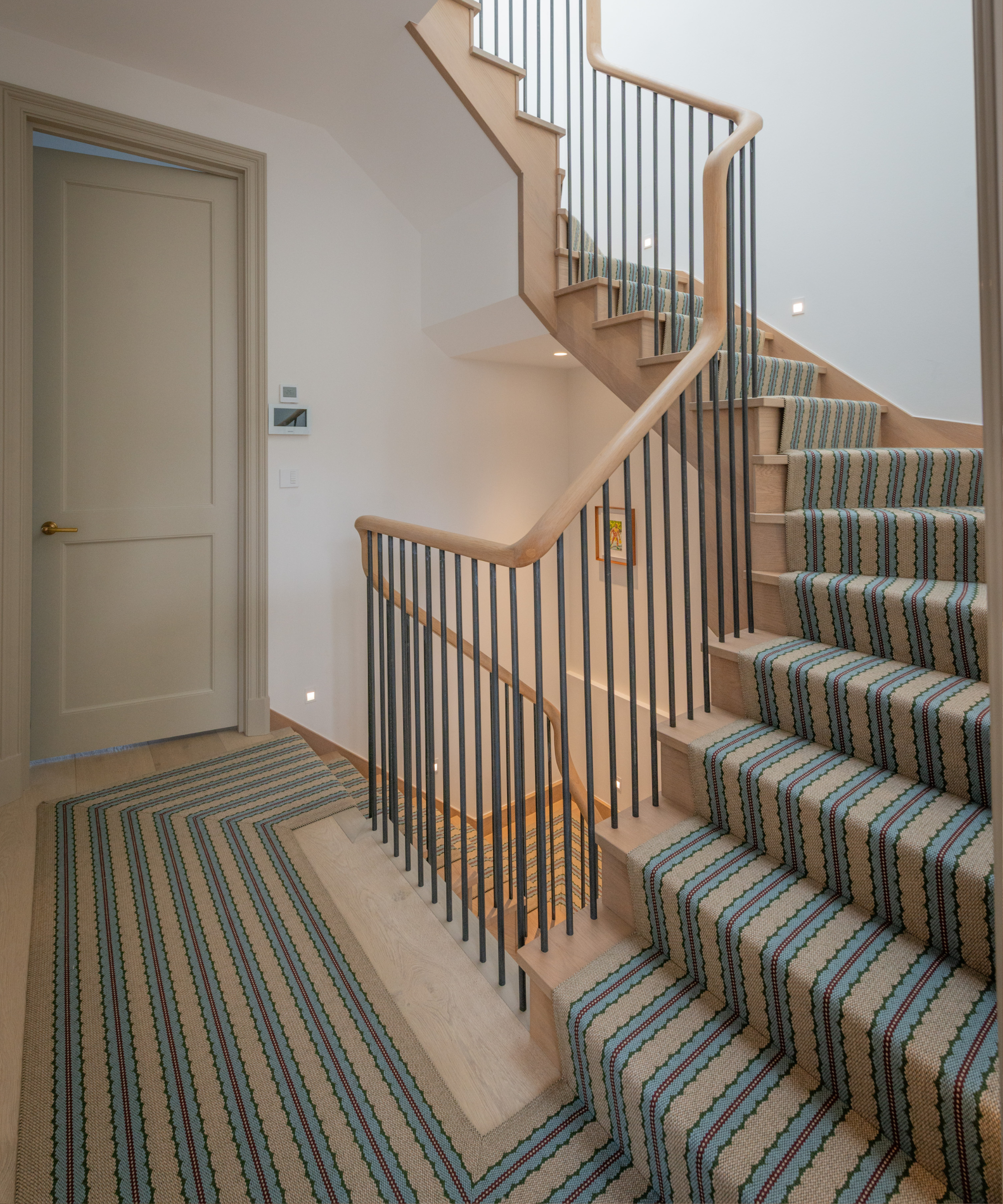 staircasew with blue, cream and red stripe runner down stairs and middle landing