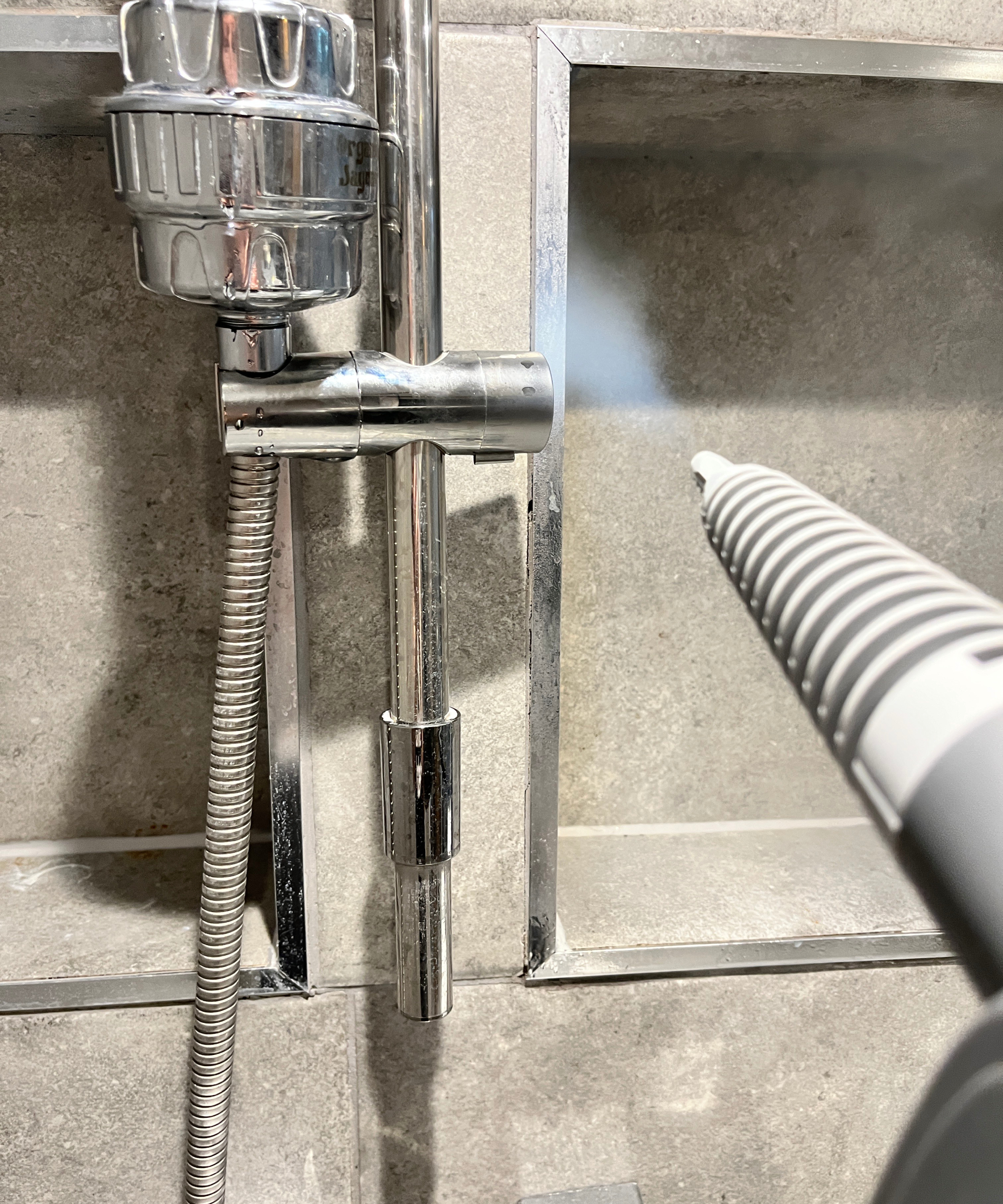 steam cleaner being used on shower and recessed shelving