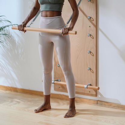 A woman working out in a studio with one of the best Pilates bars