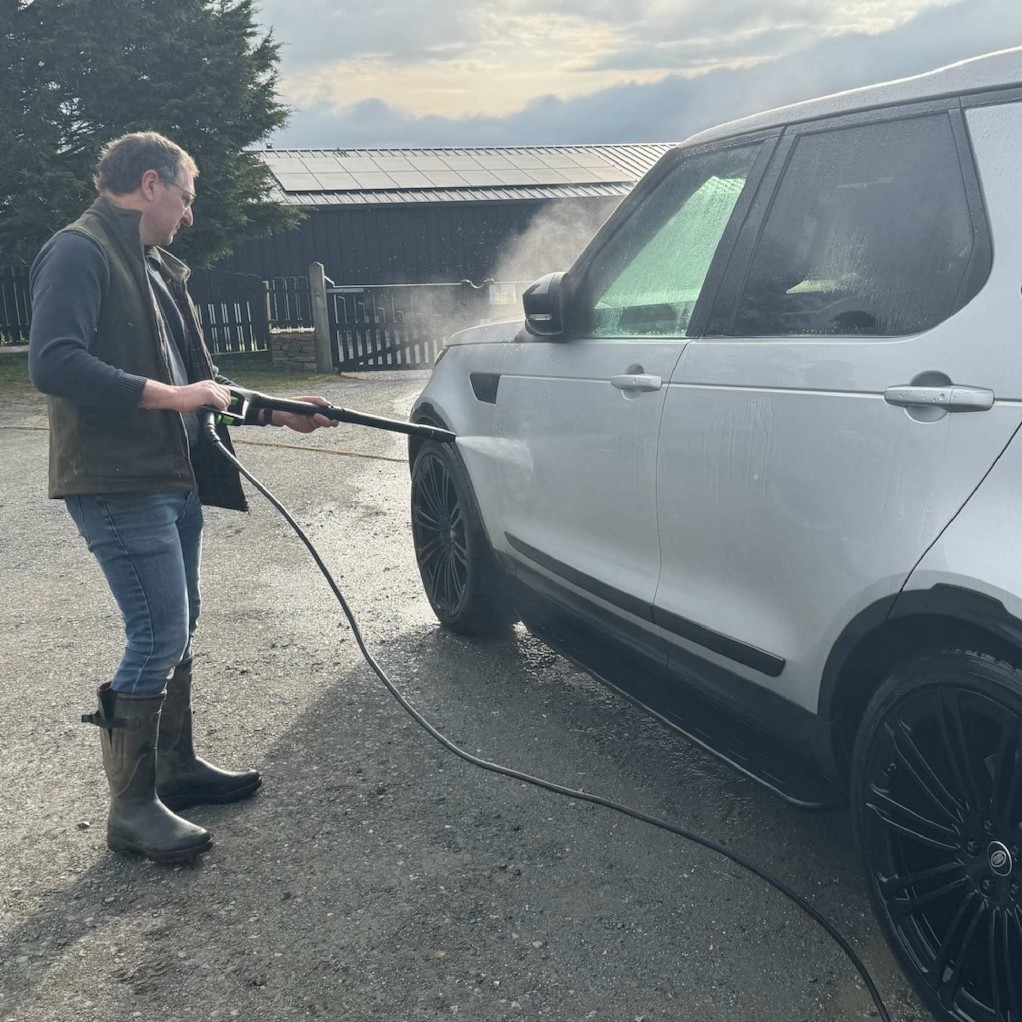 man using the greenworks g40 pressure washer on a white car