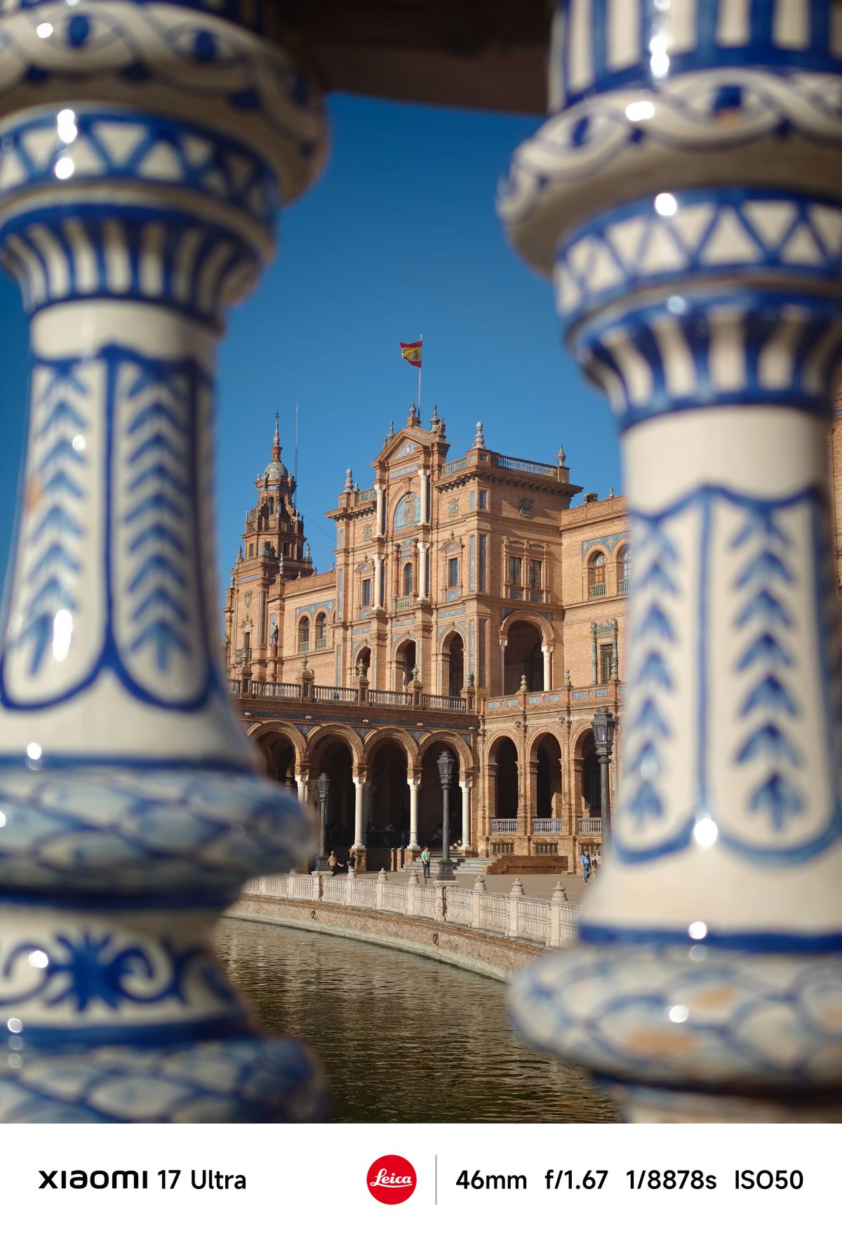 Plaza de Espa&ntilde;a building framed between two blue-and-white ceramic balusters in the foreground.