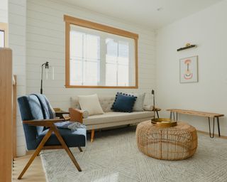 neutral living room with sofa, large window and armchair