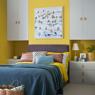 Bright yellow bedroom with IKEA storage units in the alcoves on each side of a double bed