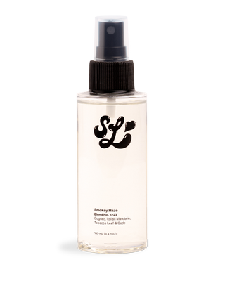 A bottle of Scent Lab Smokey Haze perfume mist in front of a plain backdrop