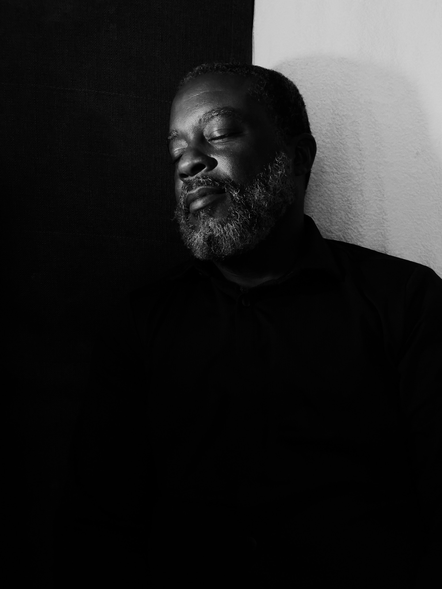 A man leaning against a black and white wall