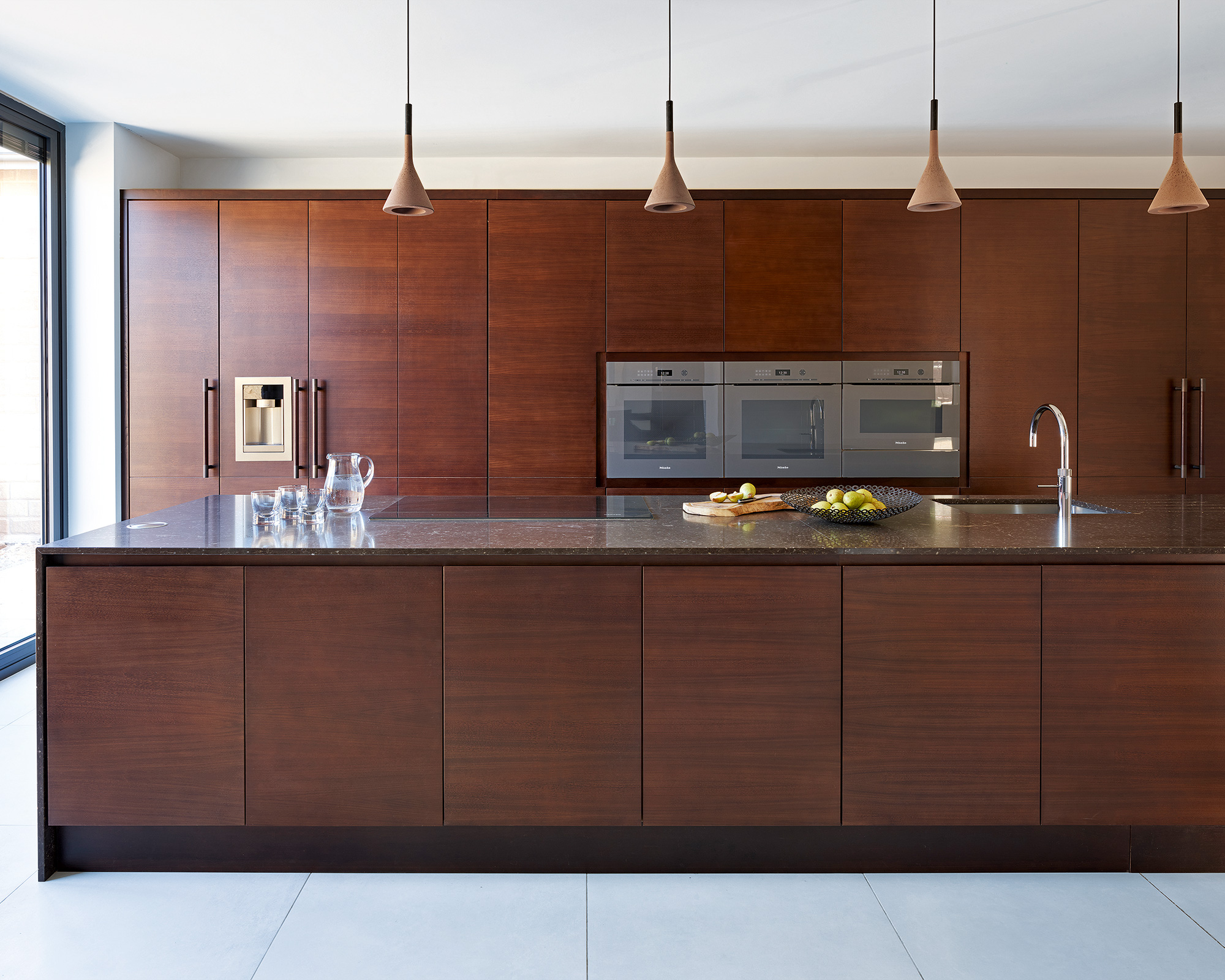 Kitchen trends 2021 showing a uniform walnut island and cabinets with pendant lighting