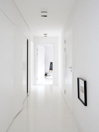 The corridor at the villa, is all white, including the floors. The only decoration is a photo framed in a black frame.