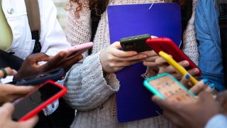 Teenagers standing in a circle holding smart phones