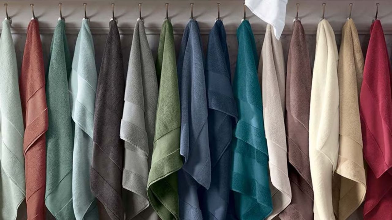 A rainbow array of Turkish towels, hanging from hooks in a bathroom.