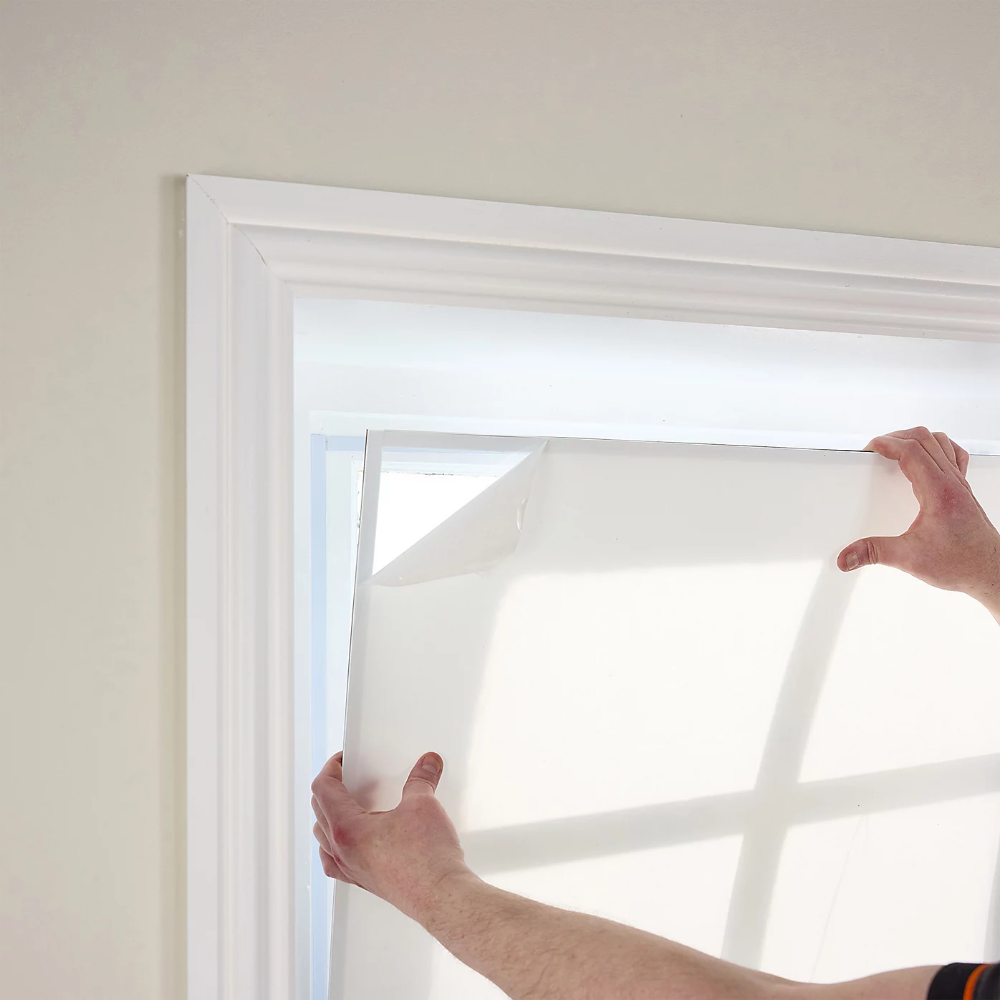 Person installing Magnetic Secondary Double-Glazing Kit onto window