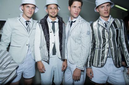 4 male models smiling, wearing different shades of grey