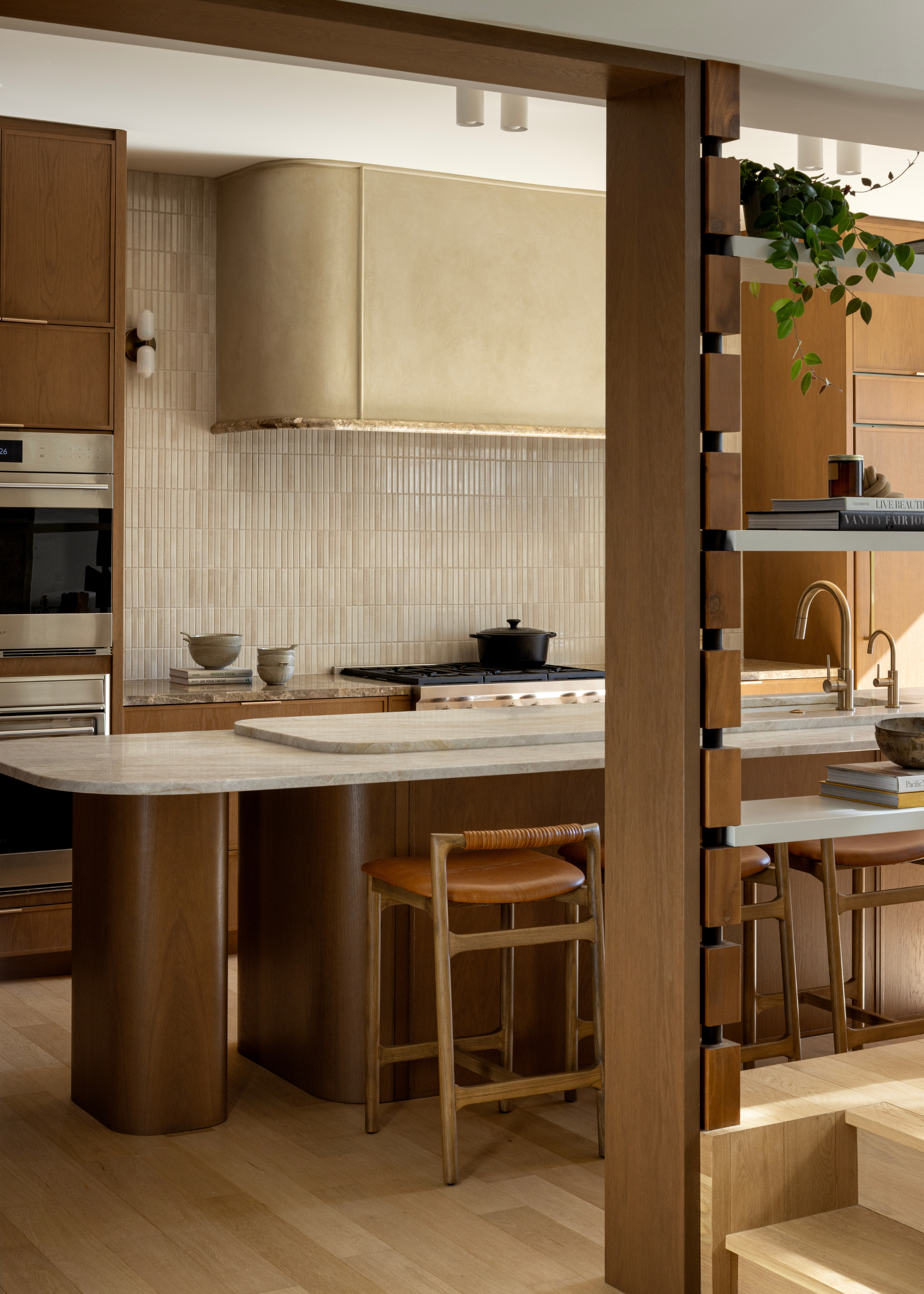 A wooden and stone kitchen with a tiled backsplash, leather and wood stools, and a black stove