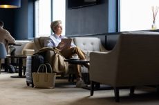 Woman with an ipad looking out the window of an airport lounge. 