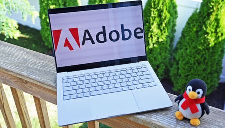 The Adobe logo featured on the ASUS Zenbook A14 laptop with a penguin mascot.