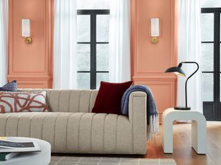 A living room with a cream sofa, a ceramic side table, and walls painted a warm terracotta