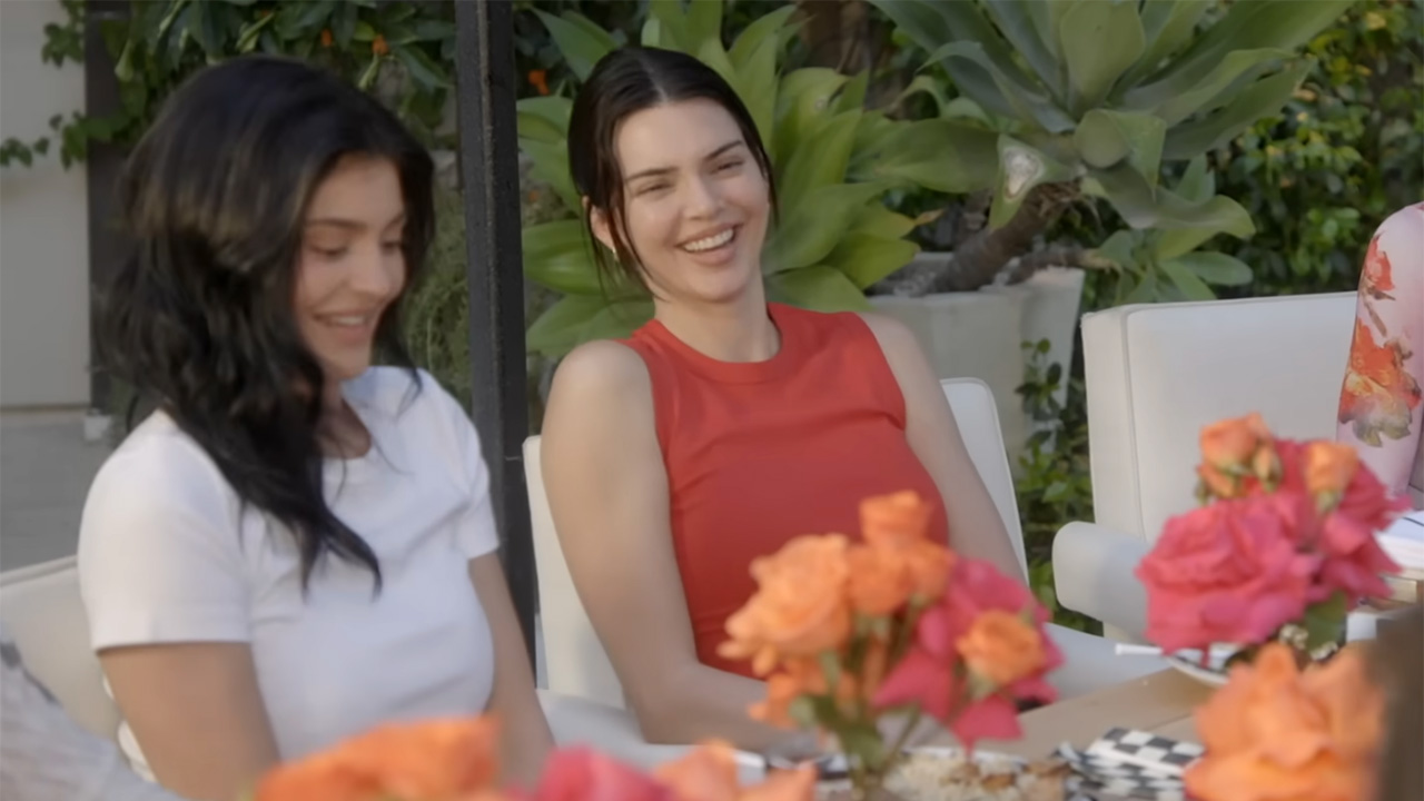 新鮮な花々で覆われた屋外ダイニングでカジュアルウェアを着たカイリーとケンダル・ジェンナー。