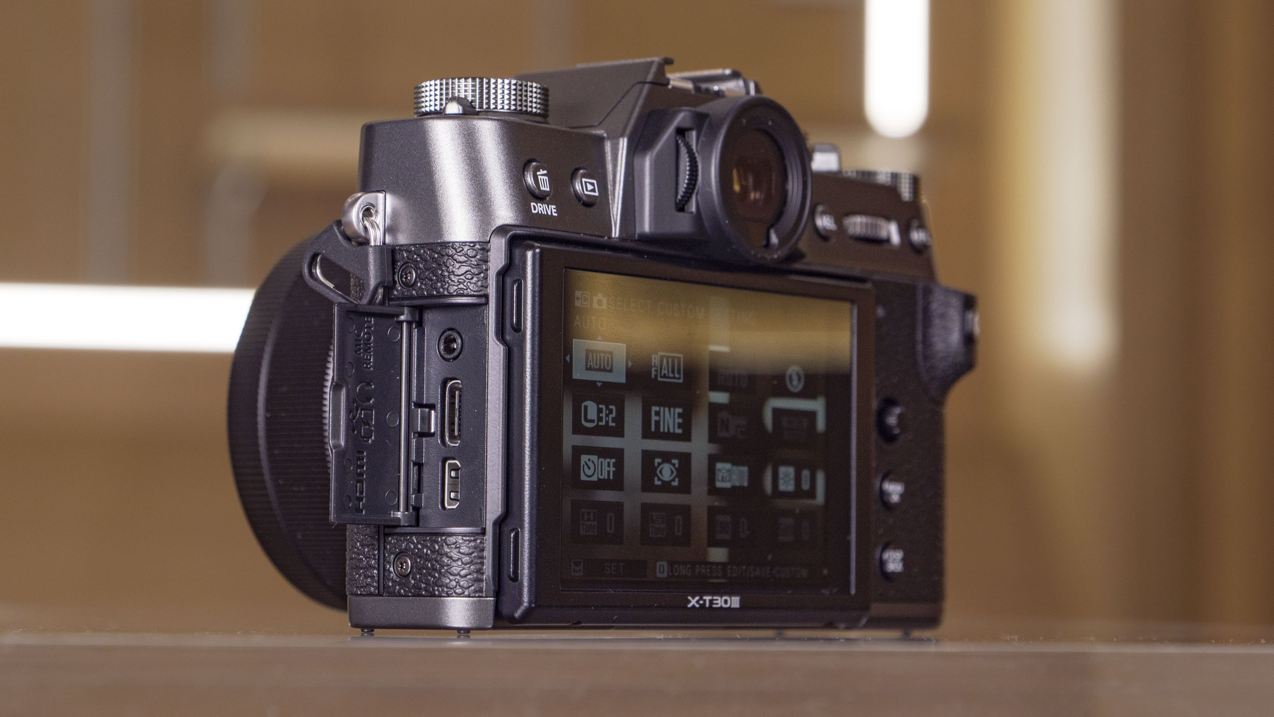 Side of the Fujifilm X-T30 III camera on a glass table, port doors open
