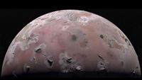 A pinkish-brown moon is seen (it's upper hemisphere). There are dark splotches on it.