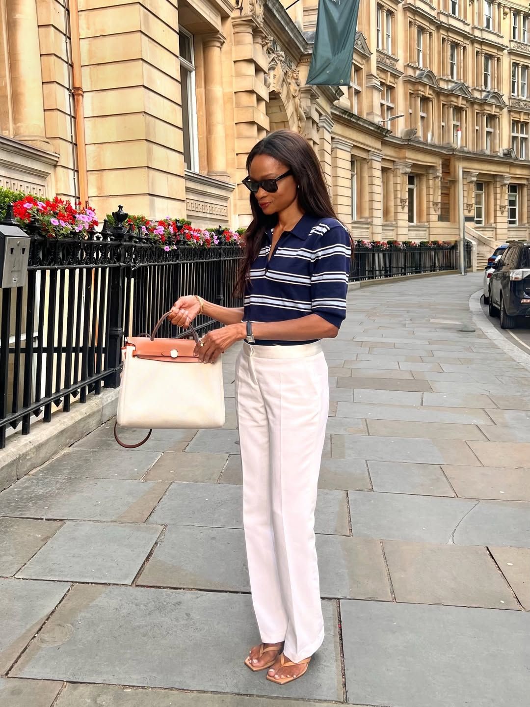 Lorna wears a striped polo shirt, white jeans and nude thong sandals