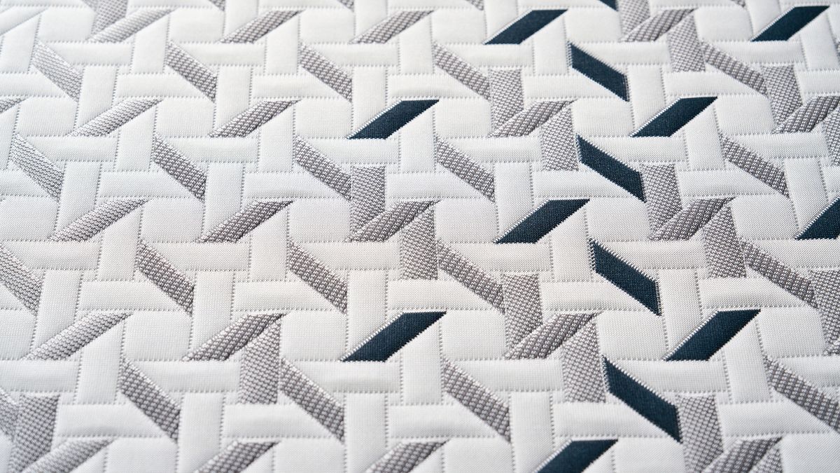 A close-up of the Nectar Ultra Hybrid mattress cooling cover, showing a geometric pattern made up of white, grey and dark blue shapes