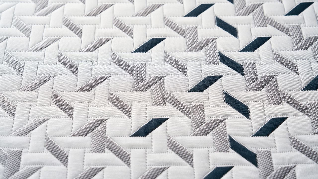 A close-up of the Nectar Ultra Hybrid mattress cooling cover, showing a geometric pattern made up of white, grey and dark blue shapes