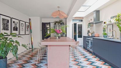 kitchen extension with colourful marble chevron flooring and pink concrete island and dark blue cabinetry 