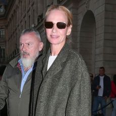 Uma Thurman steps outside in Paris wearing straight leg blue jeans with a grey blazer and navy loafers.