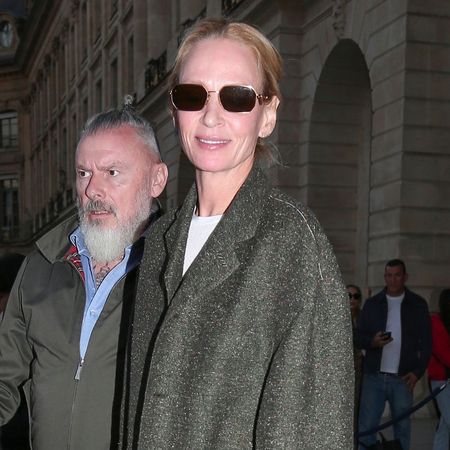 Uma Thurman steps outside in Paris wearing straight leg blue jeans with a grey blazer and navy loafers.