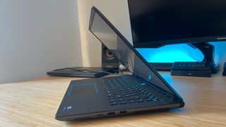 Alienware M16 R2 gaming laptop half closed on a wooden desk with blue lighting