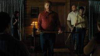 Abby Quinn, Dave Bautista, and Nikki Amuka-Bird look on as Rupert Grint holds a weapon in Knock at the Cabin.