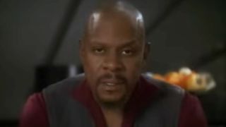 Sisko talking while seated at a table