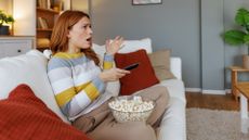 Woman looking shocked while watching TV