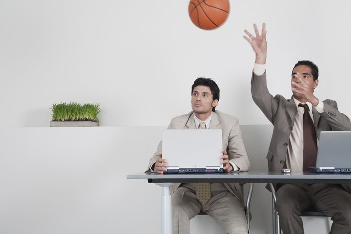  Young businessman watching colleague throwing basketball