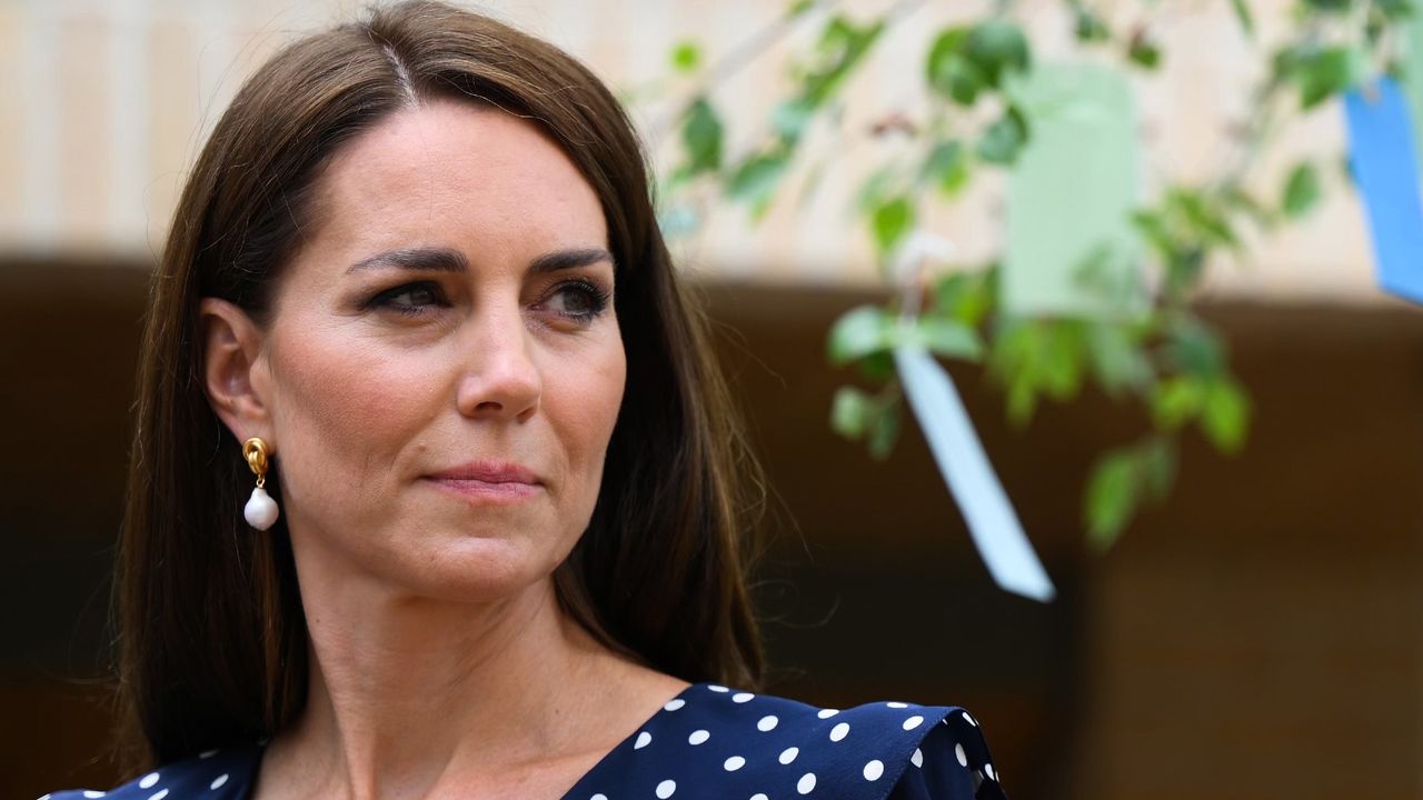 Kate Middleton with a steely expression in a blue polka dot dress