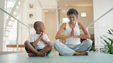 A mom teaches her son how to do yoga.
