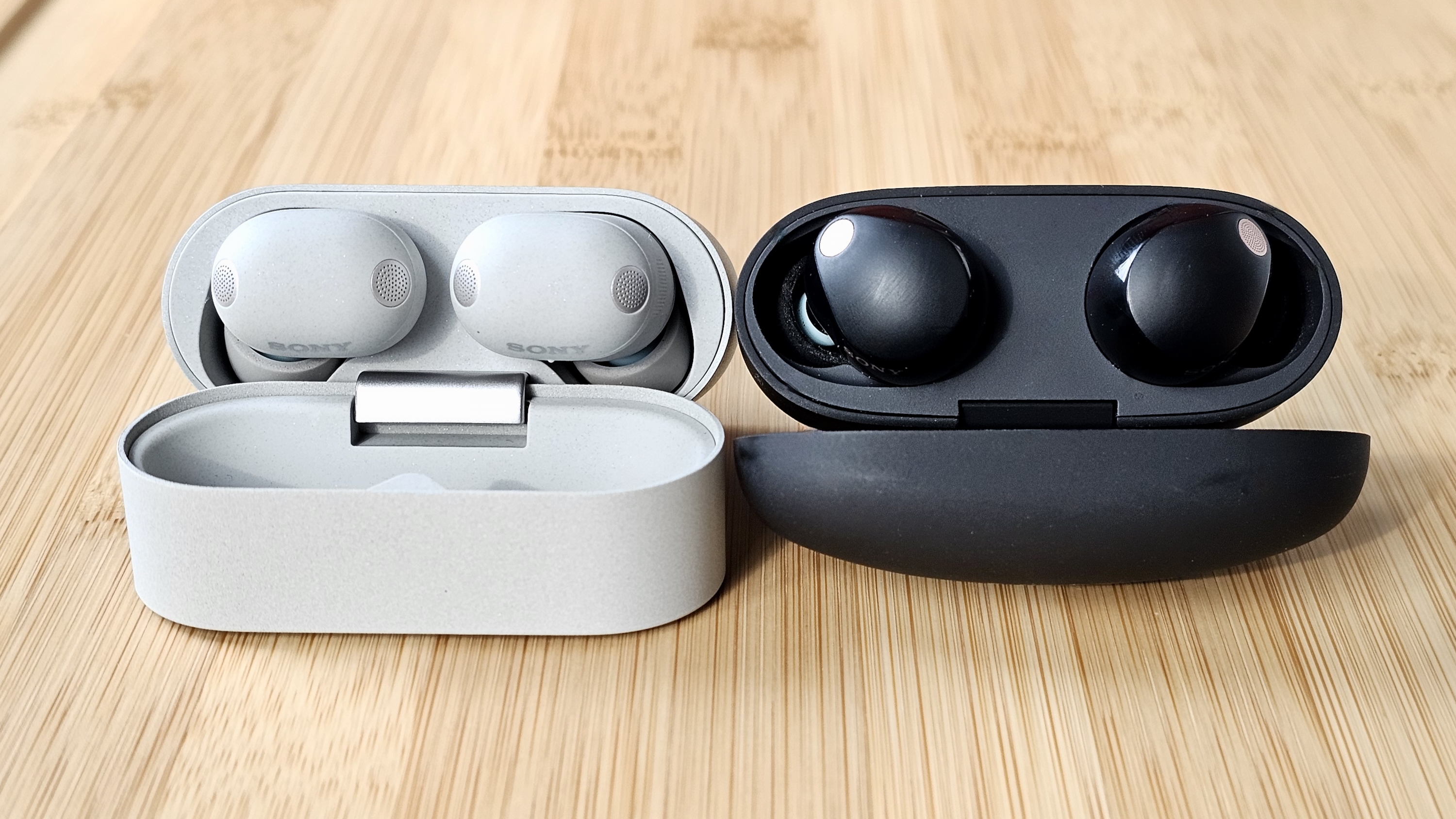 The Sony WF-1000XM6 and WF-1000XM5 side by side in a comparison, on a light wood table 