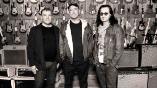 Rush posing for a photograph in a guitar shop in 2012