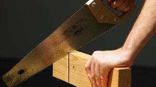 Person cutting wood with a hand saw
