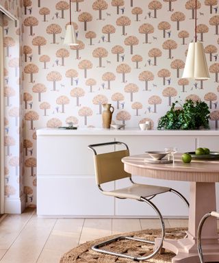 dining area with pale pink woodland pattern wallpaper, white sideboard, round dining table with modern sculptural chair