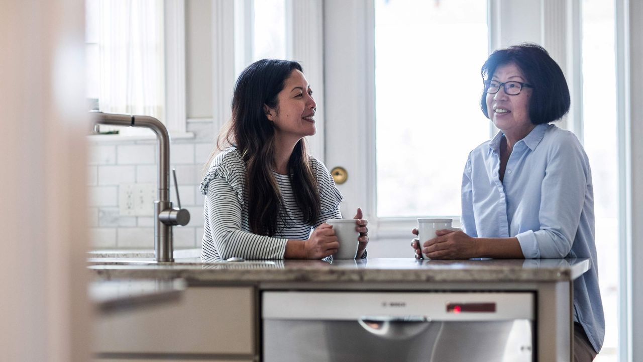 A mother and daughter drink coffee at home